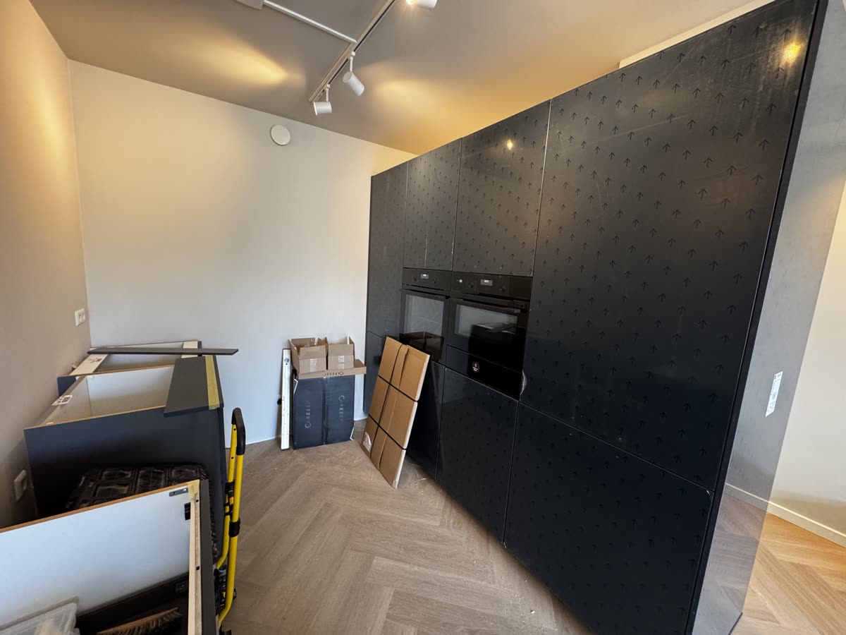 De nieuwe keuken tijdens het plaatsen: de hoge kastenwand met ovens staat, de onderkasten worden nog gemonteerd